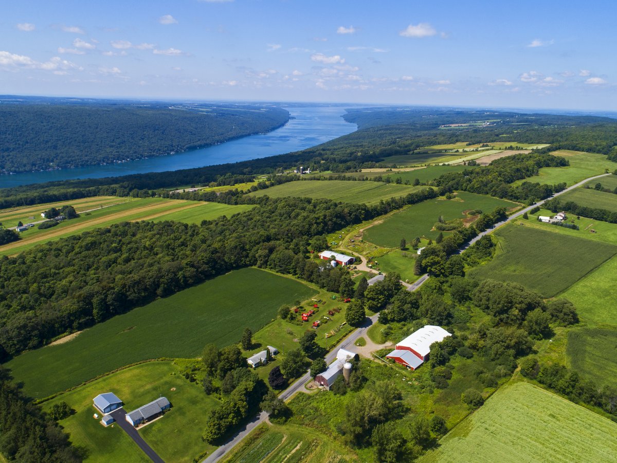 An aerial view of farm fields, buildings, and Skaneateles Lake