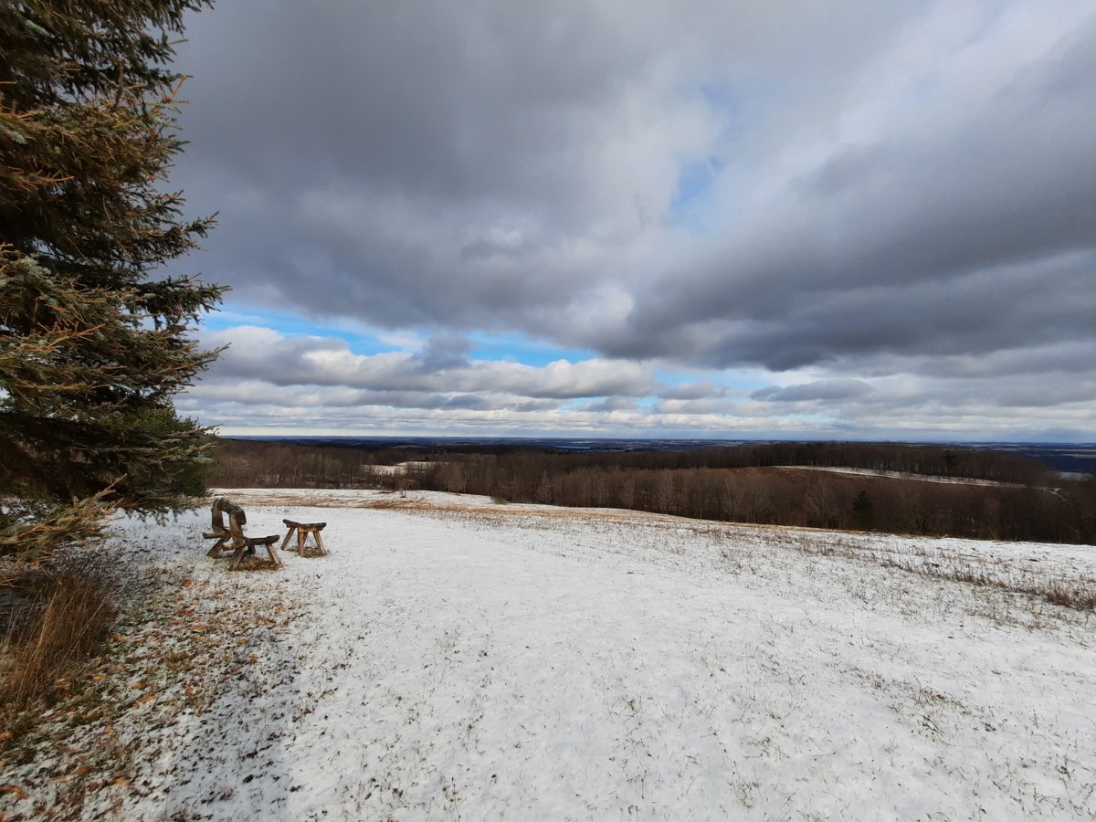 A wooden bench and open field with snow covered fields