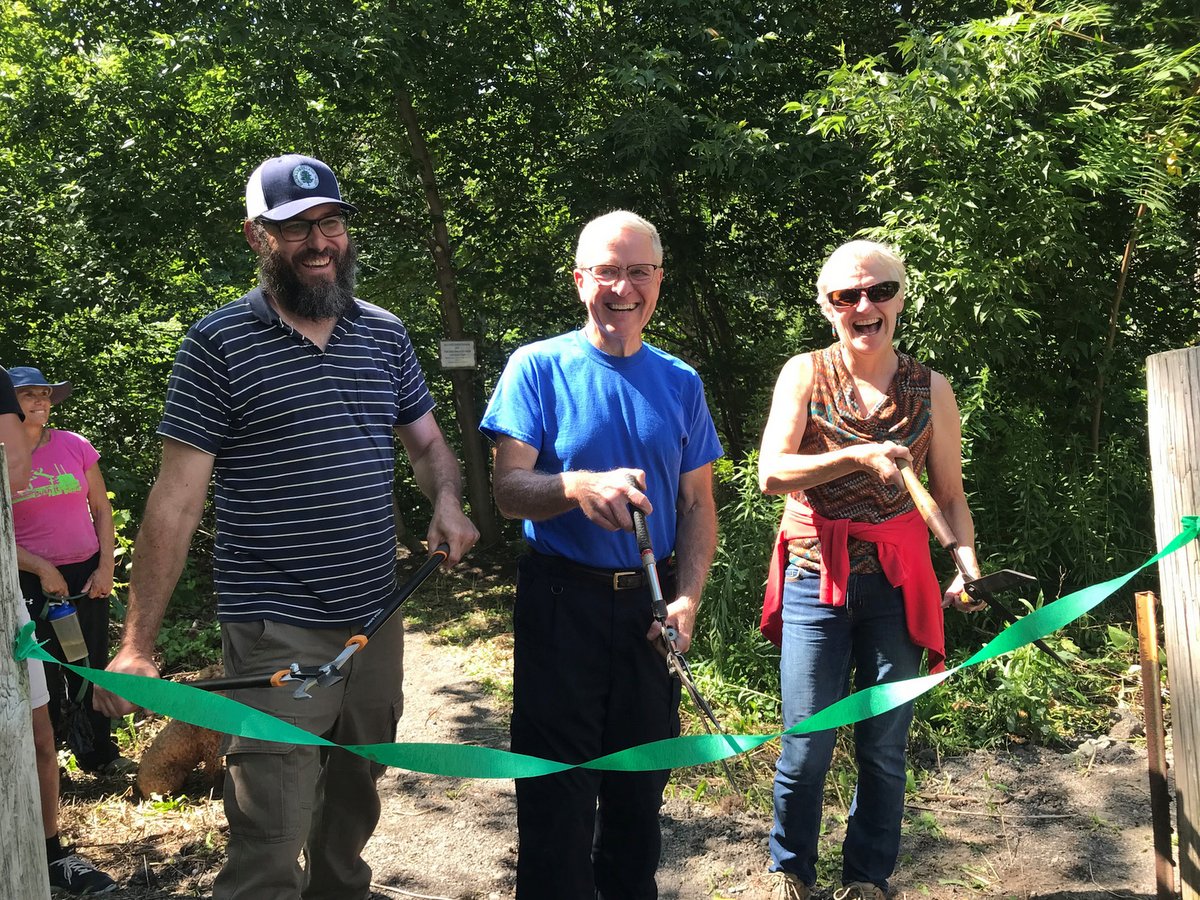 Three people cutting a ribbon at a new nature preserve