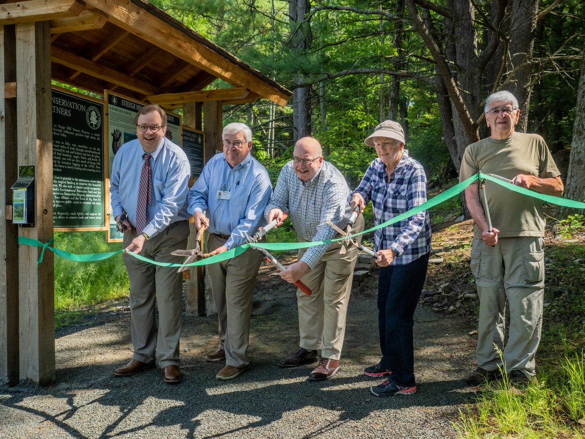 Five people cutting a ribbon to celebrate improvements to a nature preserve