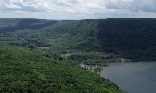 An aerial image of a lake surrounded by green hills