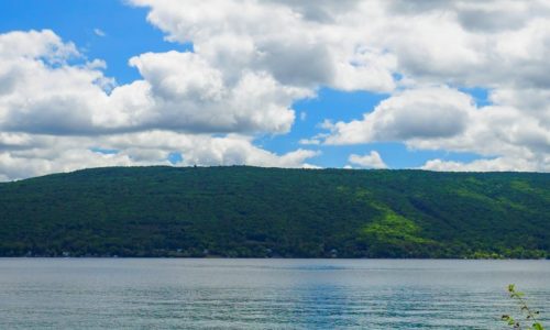 A green hill with a blue lake in the foreground