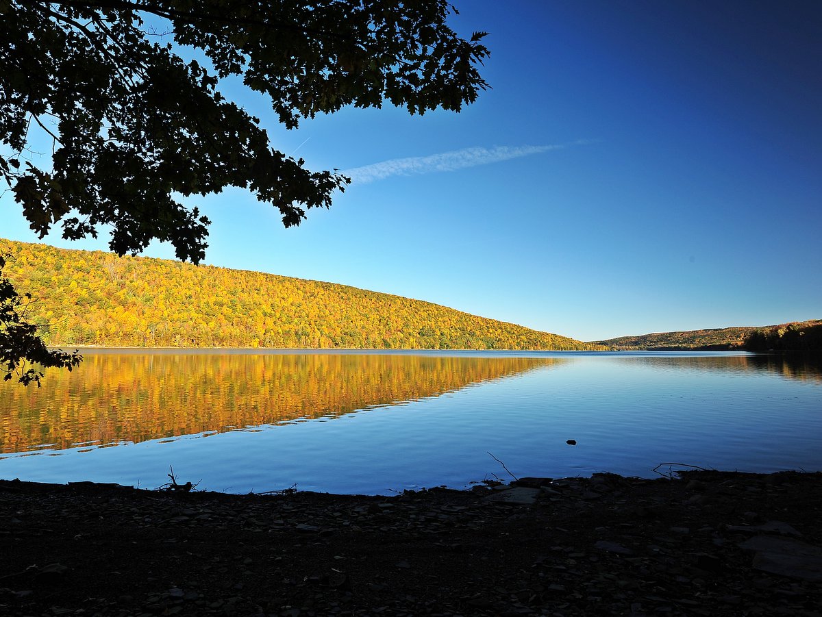 A glassy lake with bright fall colored hills in the background