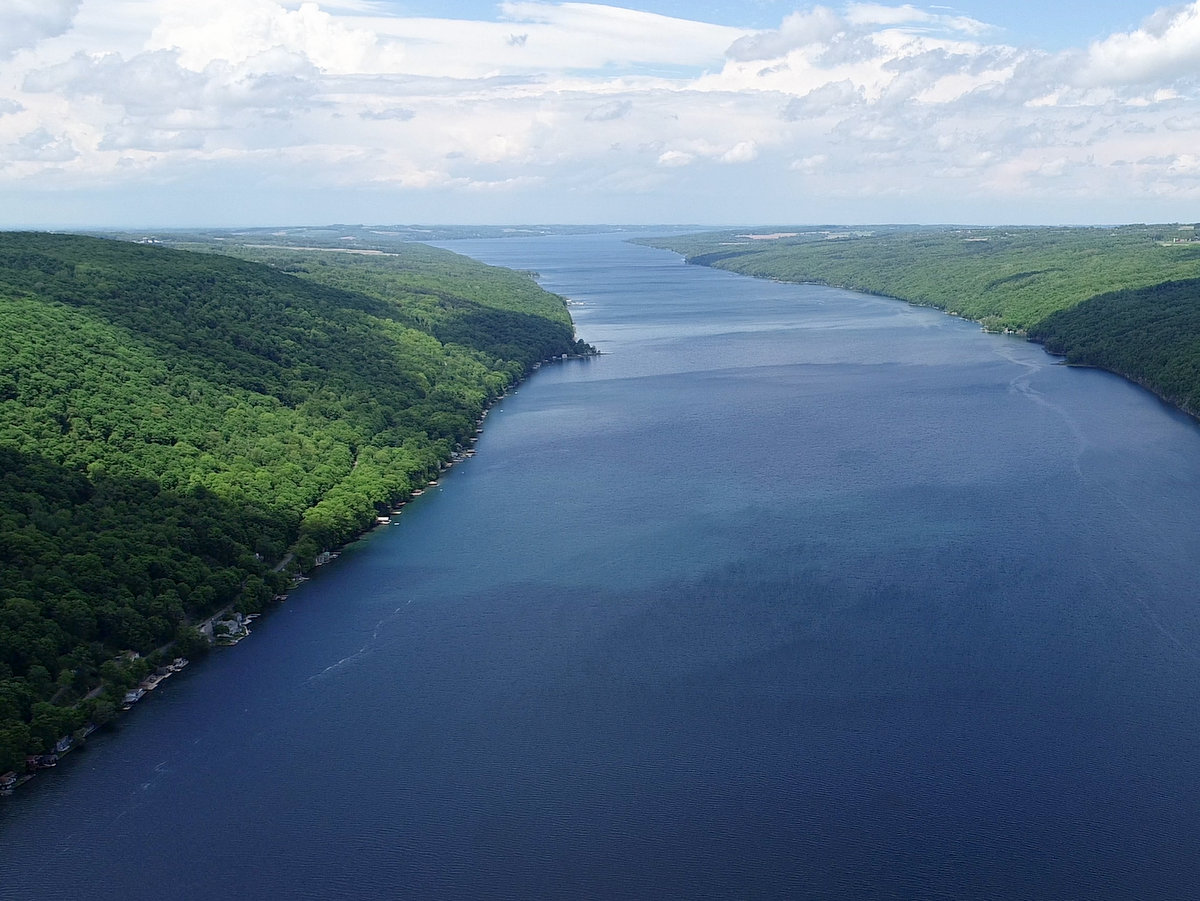 An aerial view of a lake and green hillsides