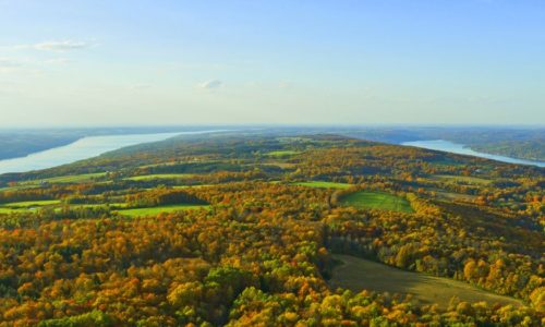 An aerial view of two lakes with fall colors in between