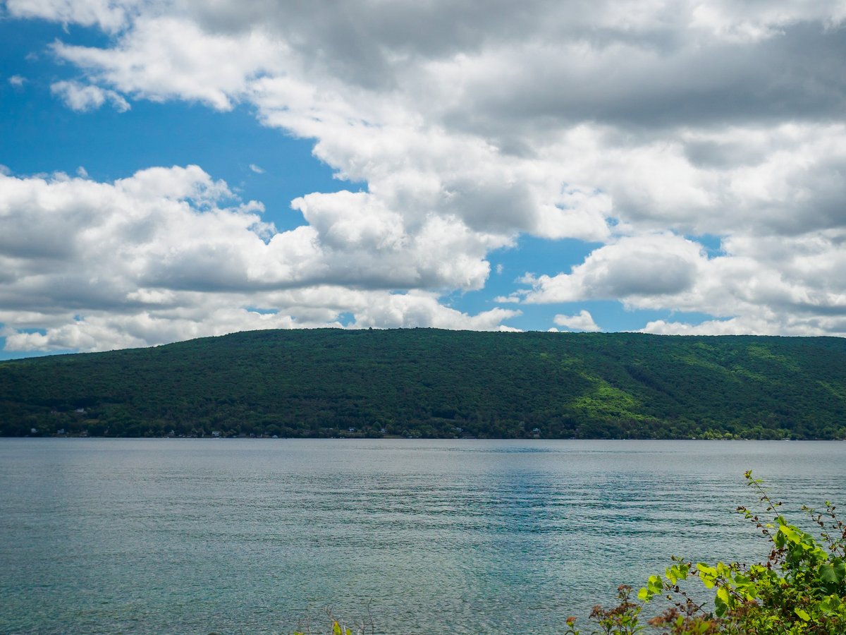 Green hills and blue sky overhead with a blue lake in the foreground 