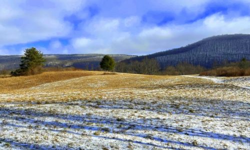 Bare hills and fields with a light dusting of snow