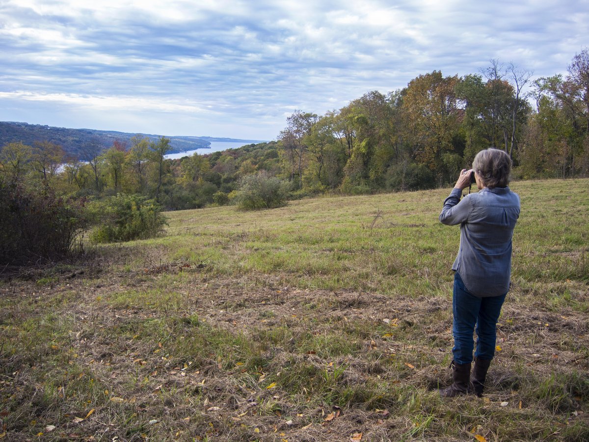 A woman looking through binoculars toward a lake