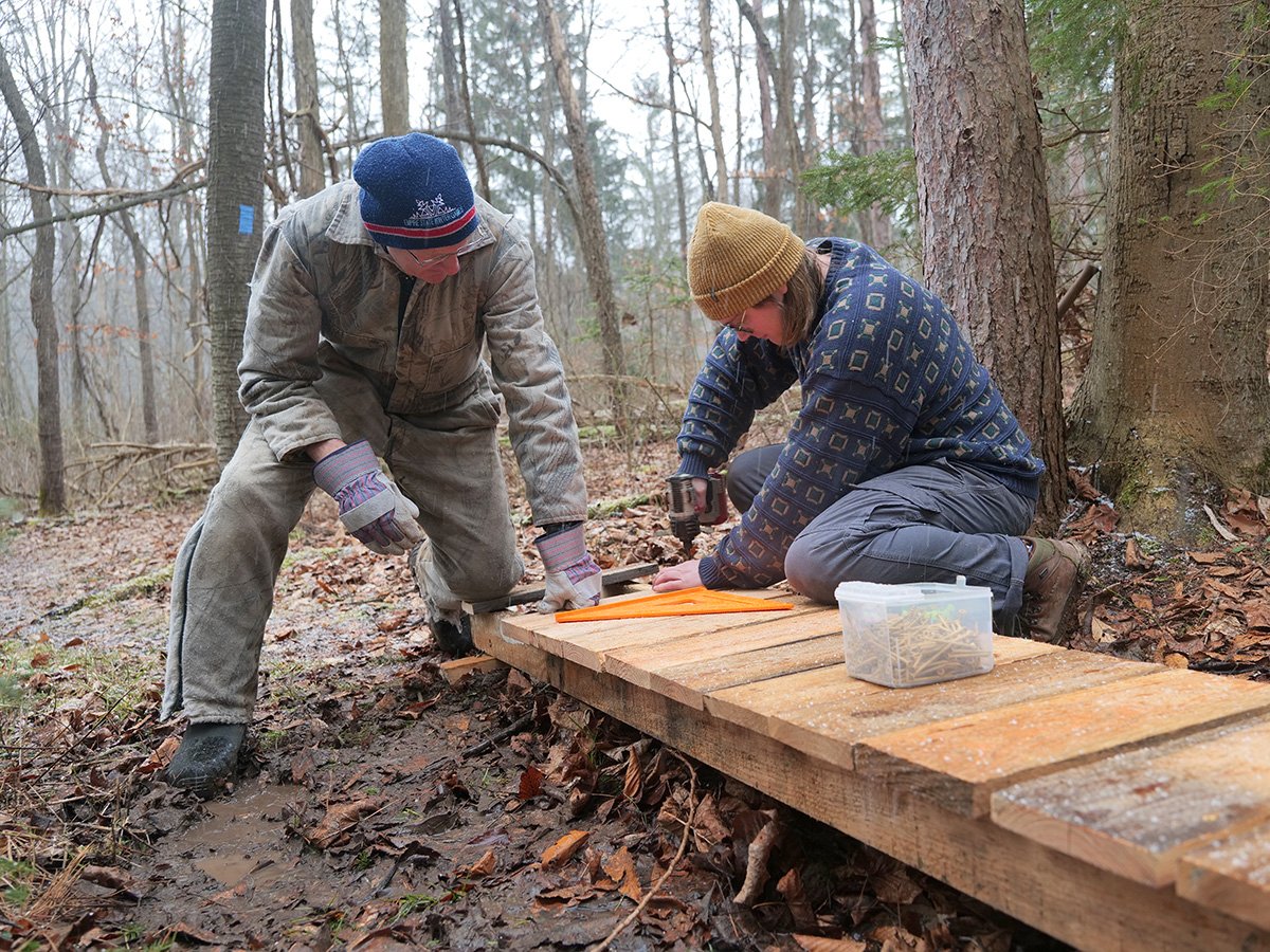 Two people building a wooden footbridge
