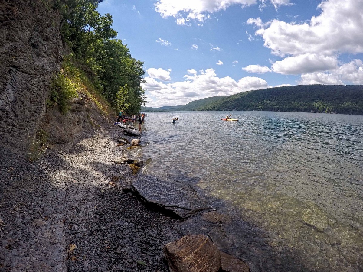 People with kayaks pulled onto the shore of a lake